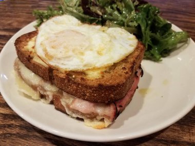 Jambonlu sandviç, erimiş peynir ve tabakta salata.