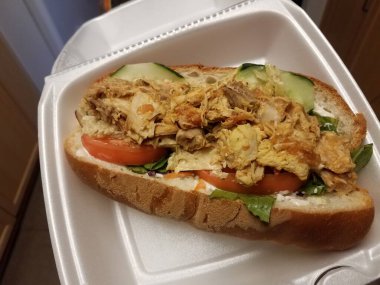 Tavuklu, domatesli ve kabında ekmek olan salatalıklı sandviç.