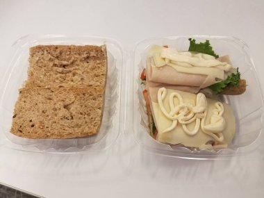 Hindi sandviçi, marul ve mayonez ile plastik bir kabın içinde.