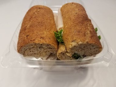 Plastik bir kabın içinde marullu hindili sandviç.