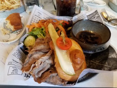 Ekmek, turşu, domates ve sos ile etli sandviç.