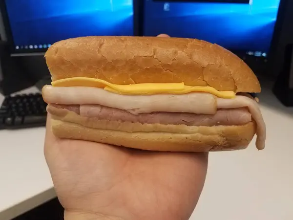 Mão Segurando Peru Presunto Queijo Sanduíche Sobre Mesa Com Monitores — Fotografia de Stock