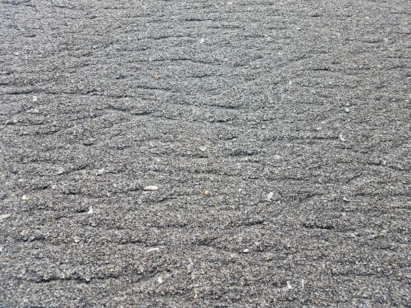 grey sand or soil on the ground at the beach with pebbles or stones or shells