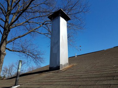 Uzun metal bacalı kiremitli çatı veya baca ve ağaç