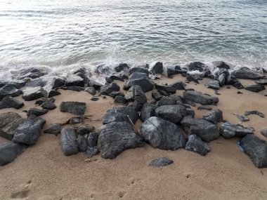 Kayalar, kum ve su kıyıda veya kıyıda dalgalar