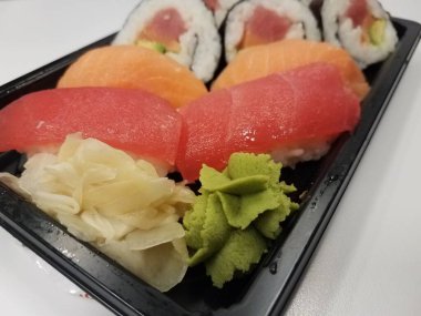 Kırmızı ton balığı, portakal somonu, pirinç ve siyah plastik bir kabın içinde deniz yosunu suşisi.