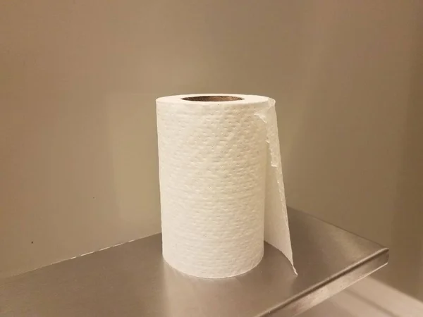 roll of white toilet paper or tissue on metal shelf in bathroom or restroom stall