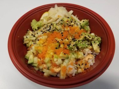 Suşi pilavlı kırmızı kase, salatalık, balık yumurtası ve avokado.