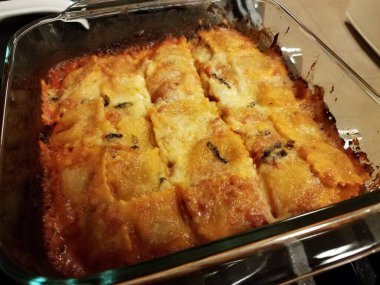 Fırında pişmiş peynirli ravioli fırının üzerinde cam kabın içinde.