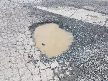 Çamur ve su birikintisi siyah çatlamış asfaltta