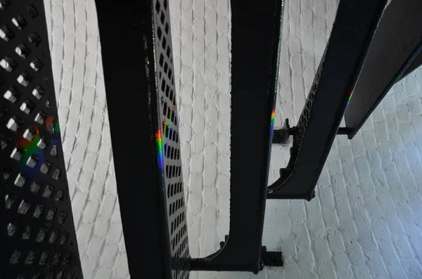 black iron stairs or steps in a lighthouse with rainbow or spectrum