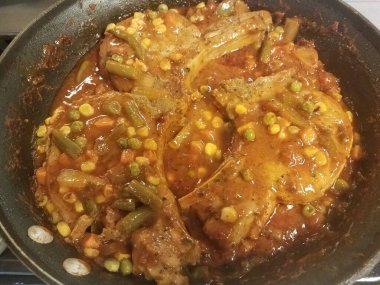 Tavada sebze ve sosla pişen domuz pirzolası.