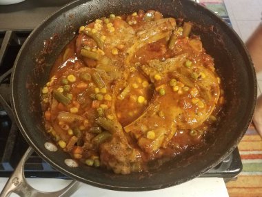 Tavada sebze ve sosla pişen domuz pirzolası.