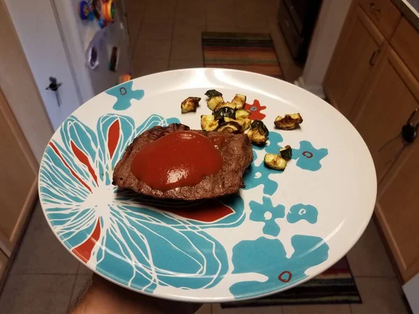 Mão Segurando Prato Com Bife Ketchup Abobrinha Cozinha — Fotografia de Stock