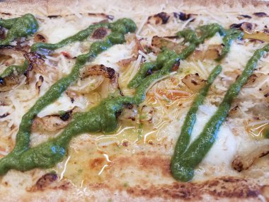 Peynirli, sarımsaklı, yeşil soslu ve soğanlı pizza.