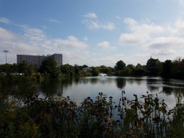 Göllü park, çeşmeli bank ve arka planda bina.