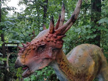 Ormanda veya ormanda boynuzları olan turuncu bir dinozor.