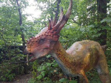 Ormanda veya ormanda boynuzları olan turuncu bir dinozor.