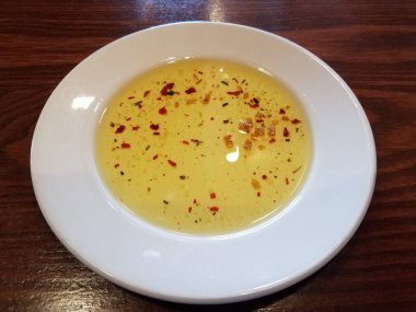 Biber ve baharatlı zeytinyağı ve kahverengi ahşap masada beyaz tabakta sarımsak.