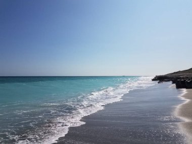 Okyanus suyu ve dalgalar kumsalda ve mavi gökyüzünde