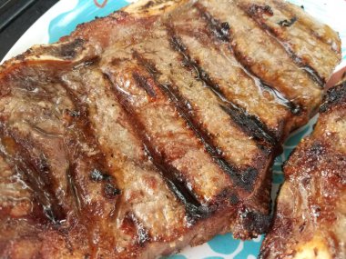 İki sulu ızgara biftek, beyaz ve mavi tabakta.