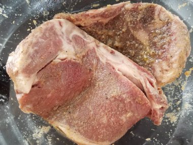 Cam bir kasede oturan iki baharatlı biftek.