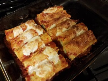 Fırında pişmiş manicotti makarna, fırında cam kasede peynir.