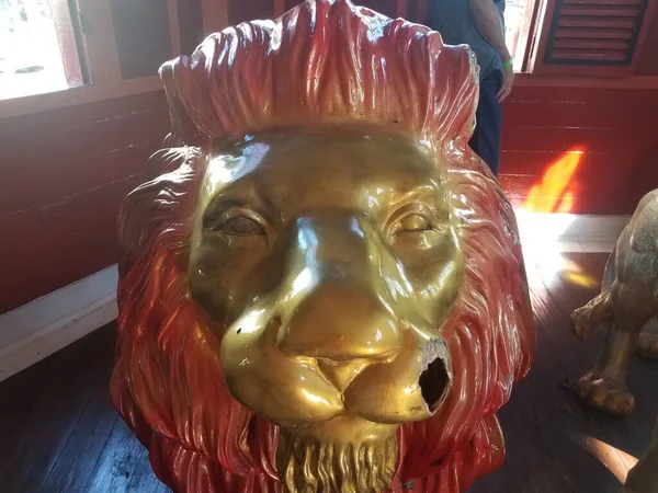 lion animal statue with face and painted gold and hole in face