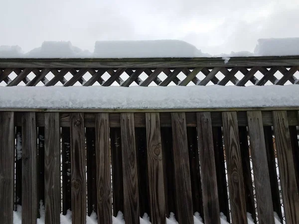 inches of white snow on wooden fence