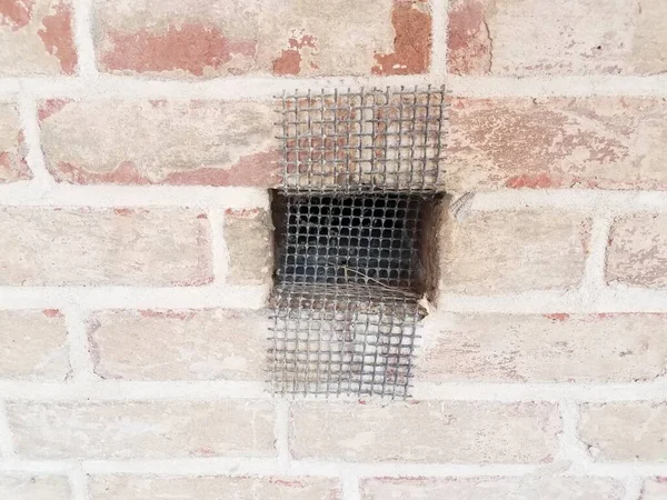 用金属丝网或筛子在红砖墙或石墙上打孔 — 图库照片