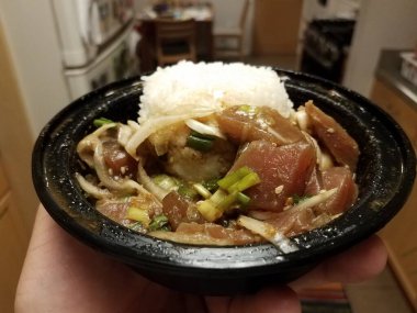 Mutfakta bir kase çiğ ton balığı, soğan ve pirinç var.