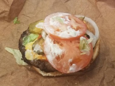 Hamburger, çörek, domates ve soslu kahverengi paket.