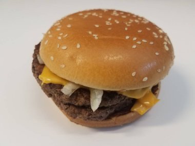 Hamburger ekmeğinde sığır eti, soğan ve peynir beyaz yüzeyde veya masada.