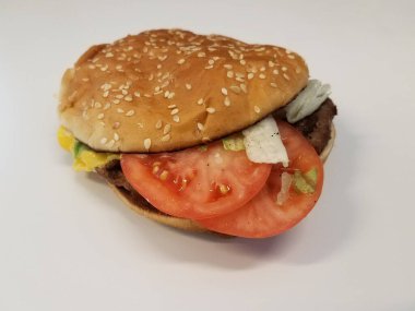 Peynirli biftek, domates ve beyaz yüzeyde çörek.