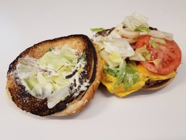 Beyaz yüzeyde peynirli ve domatesli sığır burger