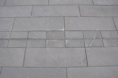 Gri taş dikdörtgen karolar ve yerde drenaj