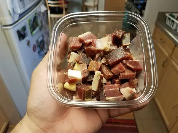 厨房里放着盛有色拉诺火腿肉的塑料容器 — 图库照片