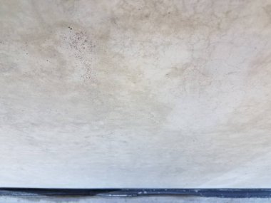 Duvarın tabanında küçük çatlaklar olan eski gri beton duvar.