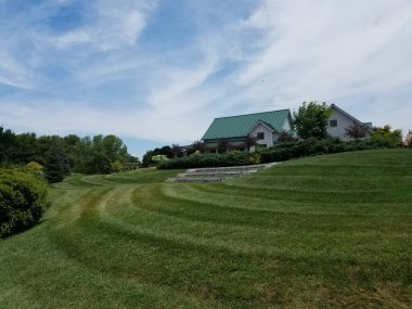 Büyük yeşil çimen alanı ve bulutlu bir bina.