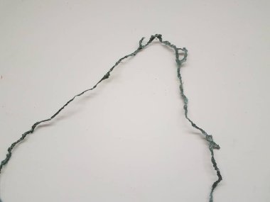 Beyaz duvar boyunca yeşil kıvrımlı düzensiz metal parçası