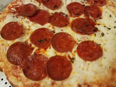 Metal fırın tepsisinde peynirli, yağlı, acı biberli pizza.