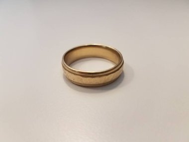 Beyaz bir yüzeyde altın bir alyans ya da bant