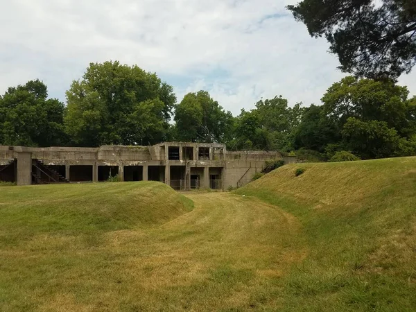 古い摩耗したセメントの建物と緑の芝生の丘 — ストック写真