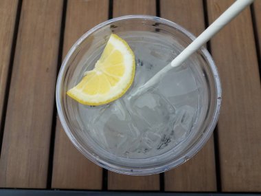 Bir bardak buzlu su limon ve saman ile ahşap masa