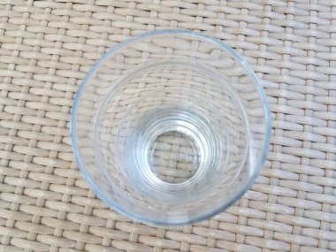 Kahverengi hasır masada uzun, berrak bir bardak.