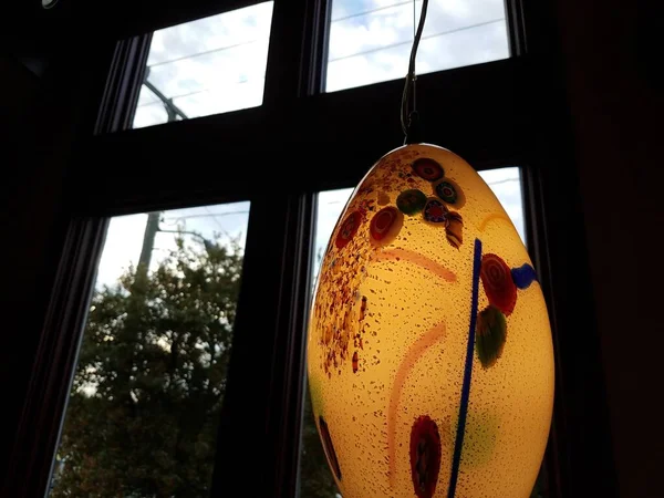 a colorful oval class light near a window