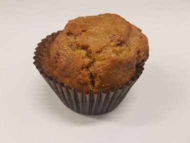 Kahverengi kek beyaz yüzeyde kahverengi kağıda sarılmış.