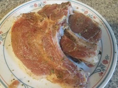 Beyaz bir tabakta birkaç baharatlı domuz pirzolası.