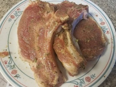 Beyaz bir tabakta birkaç baharatlı domuz pirzolası.