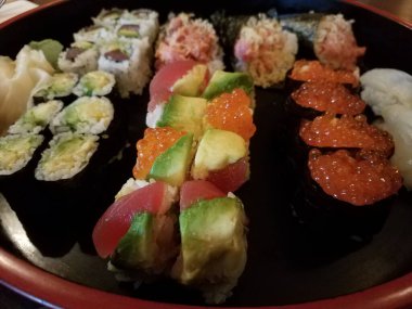 Suşi, pirinç ve balık yumurtası çeşitleri içeren büyük dairesel bir tabak.